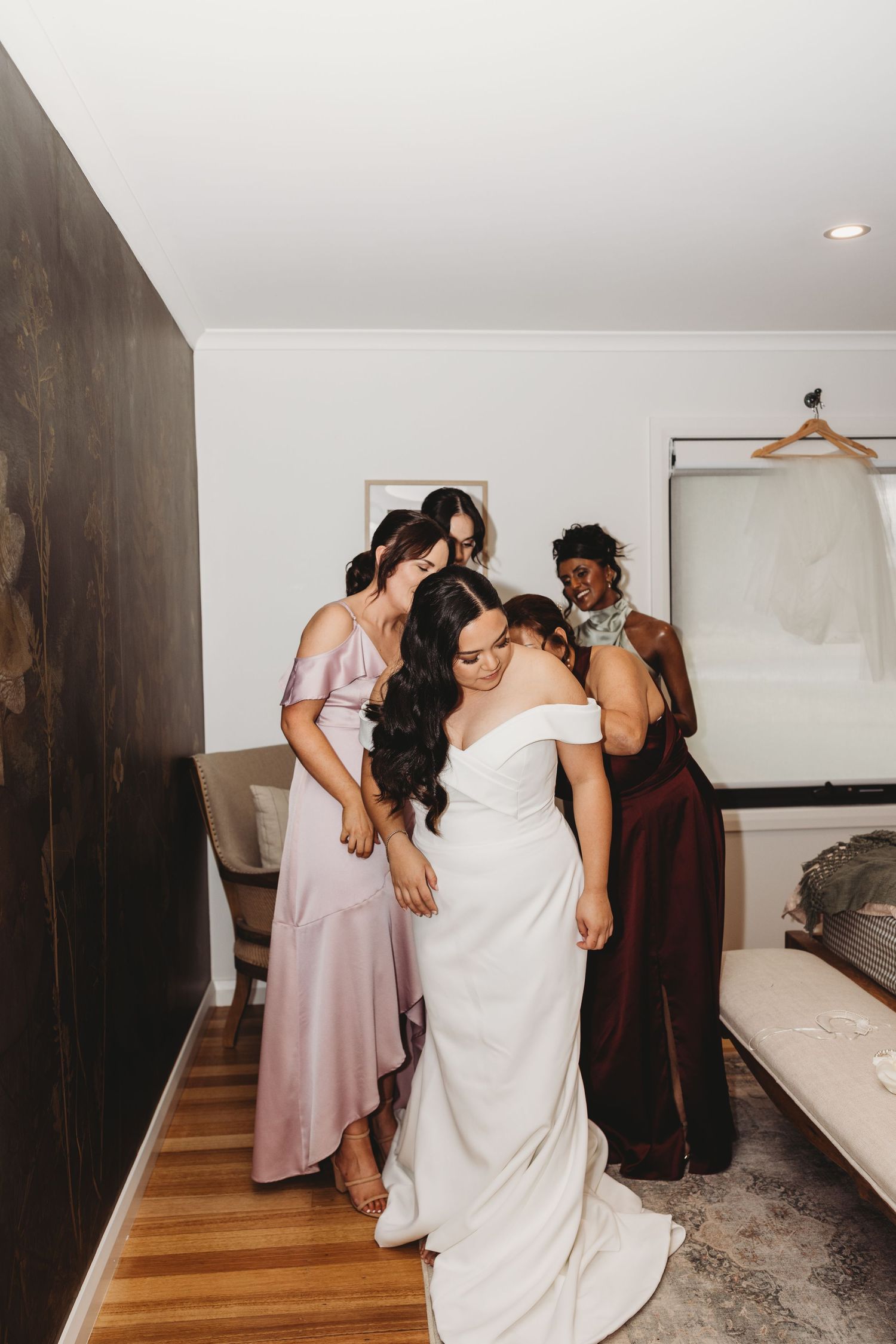 Wedding preparation scene with bridesmaids helping in getting ready room.