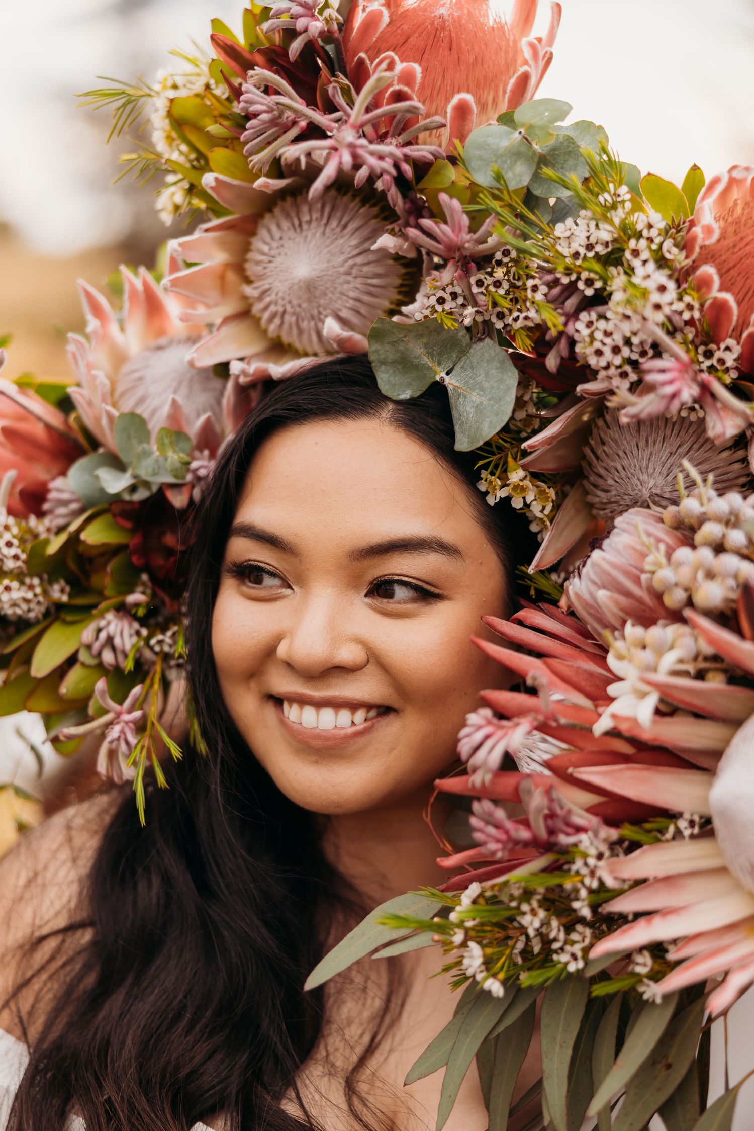 Beautiful floral crown made of proteas and native flowers in coral and pink tones.
