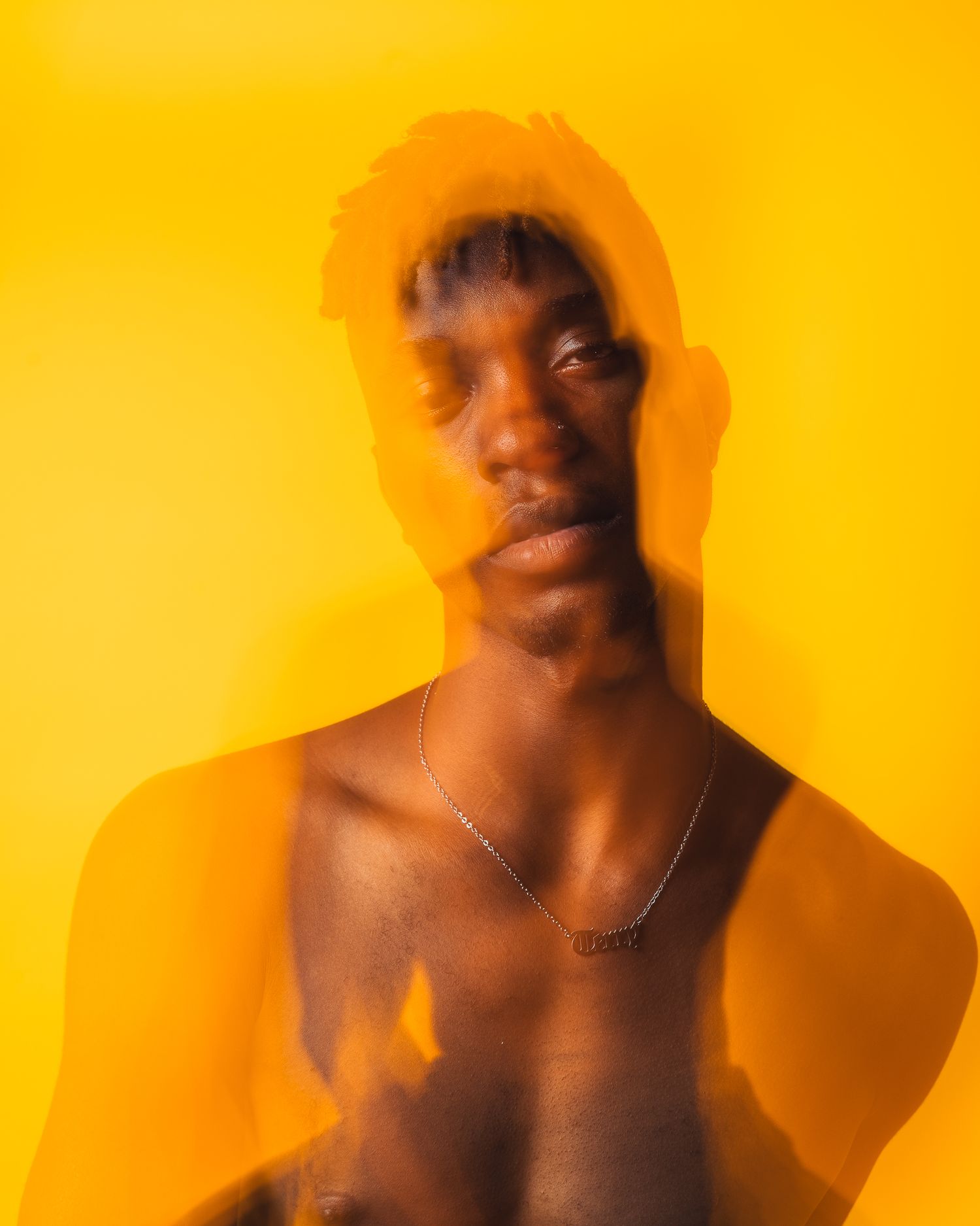 Artistic portrait with orange double exposure effect against vibrant yellow background.