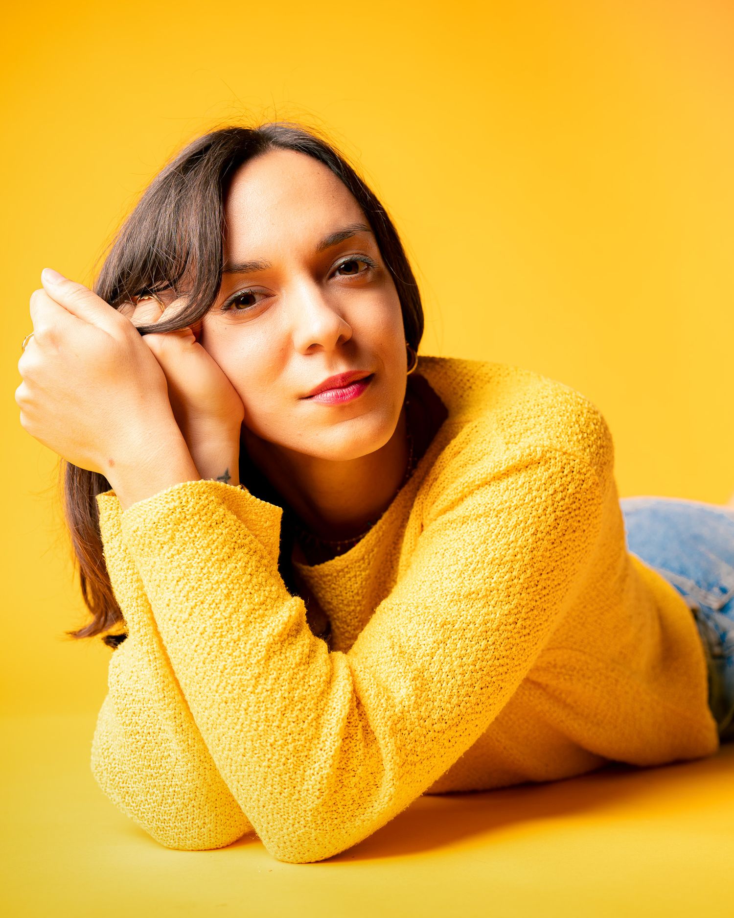 Portrait of woman in yellow sweater against bright yellow background.