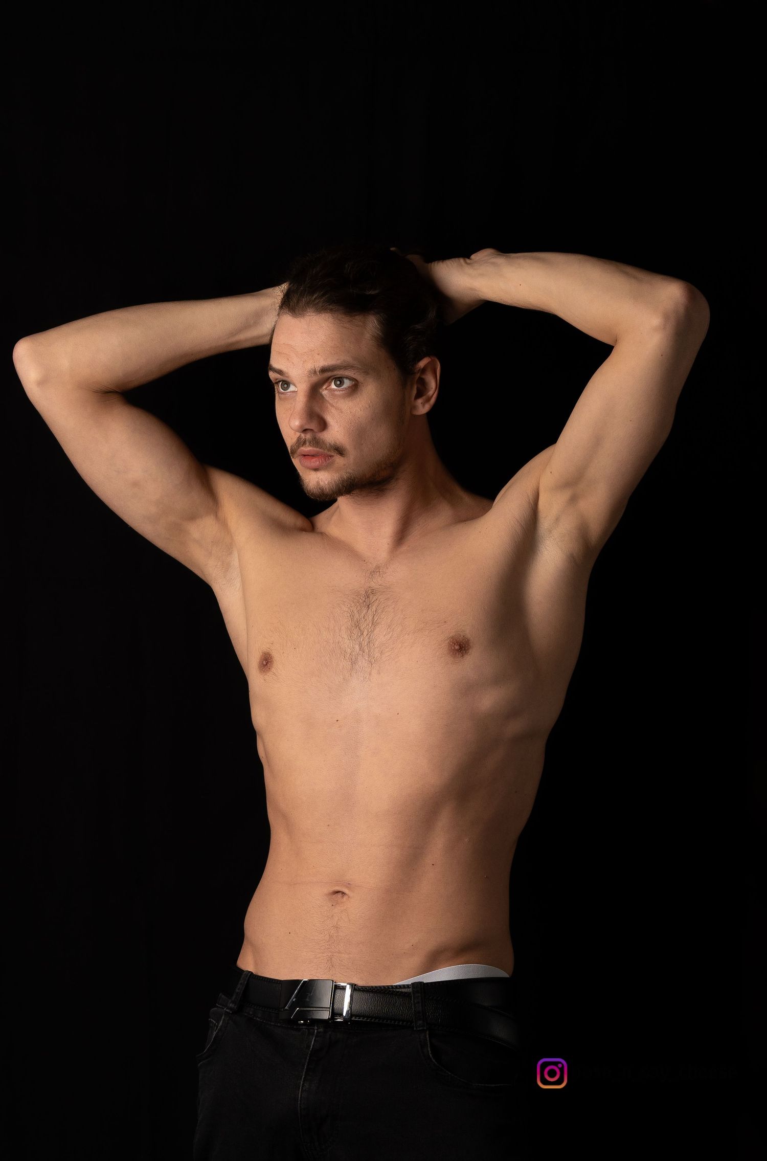 Athletic figure poses against dark background showing defined physique.