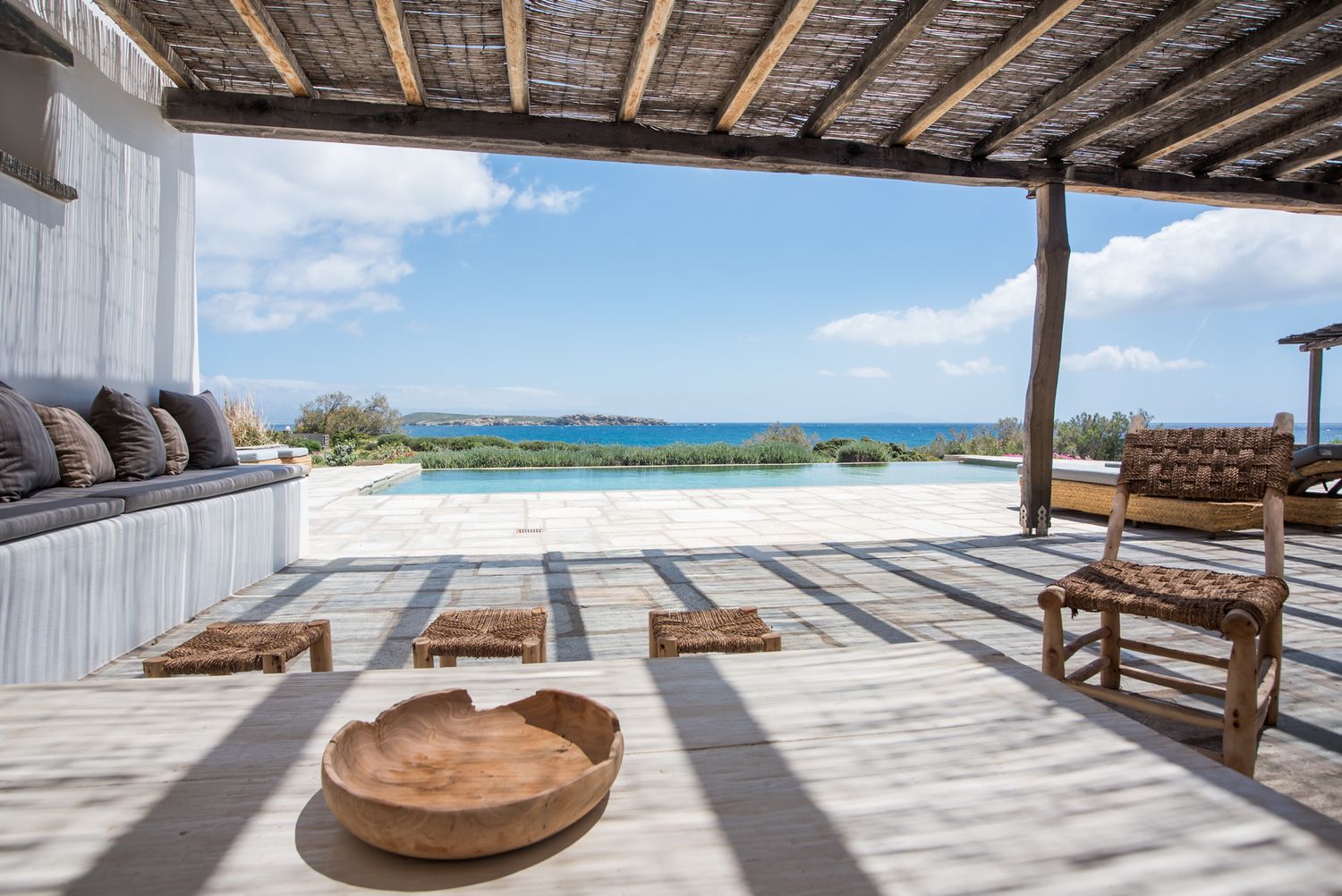 Coastal villa terrace with infinity pool overlooking ocean views and comfortable outdoor seating.