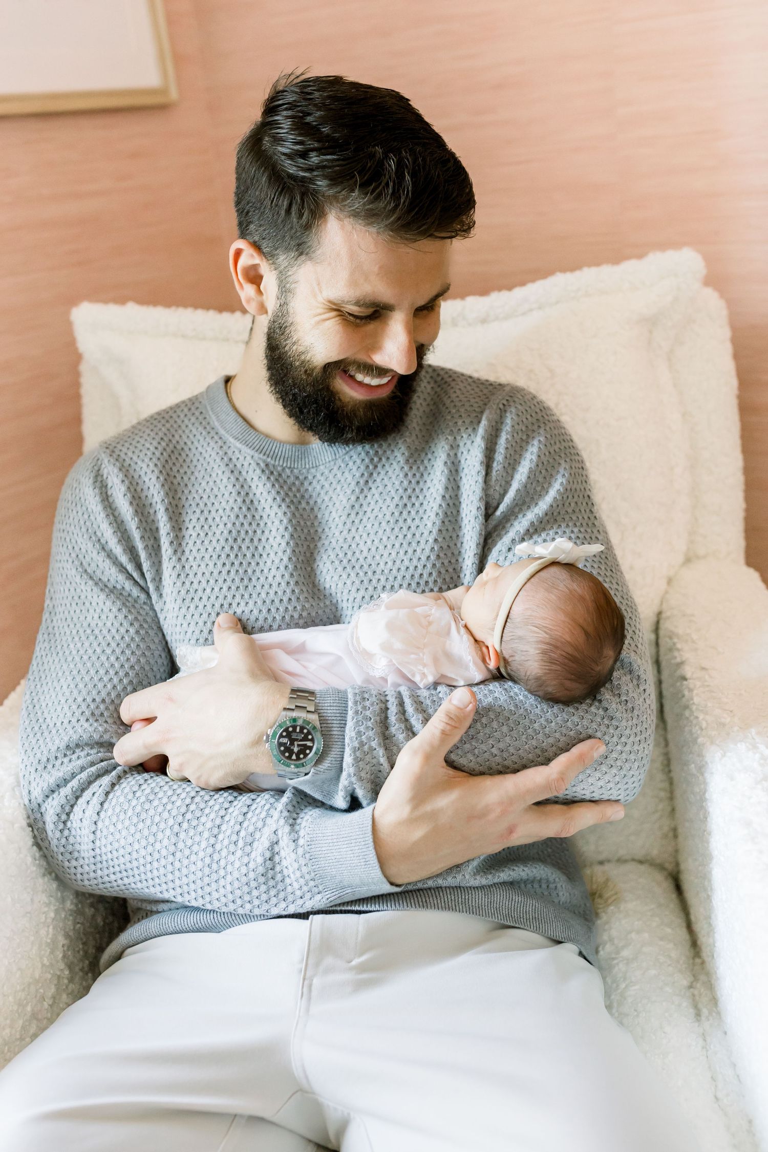 A tender moment between father and newborn baby while sitting in a comfortable armchair.