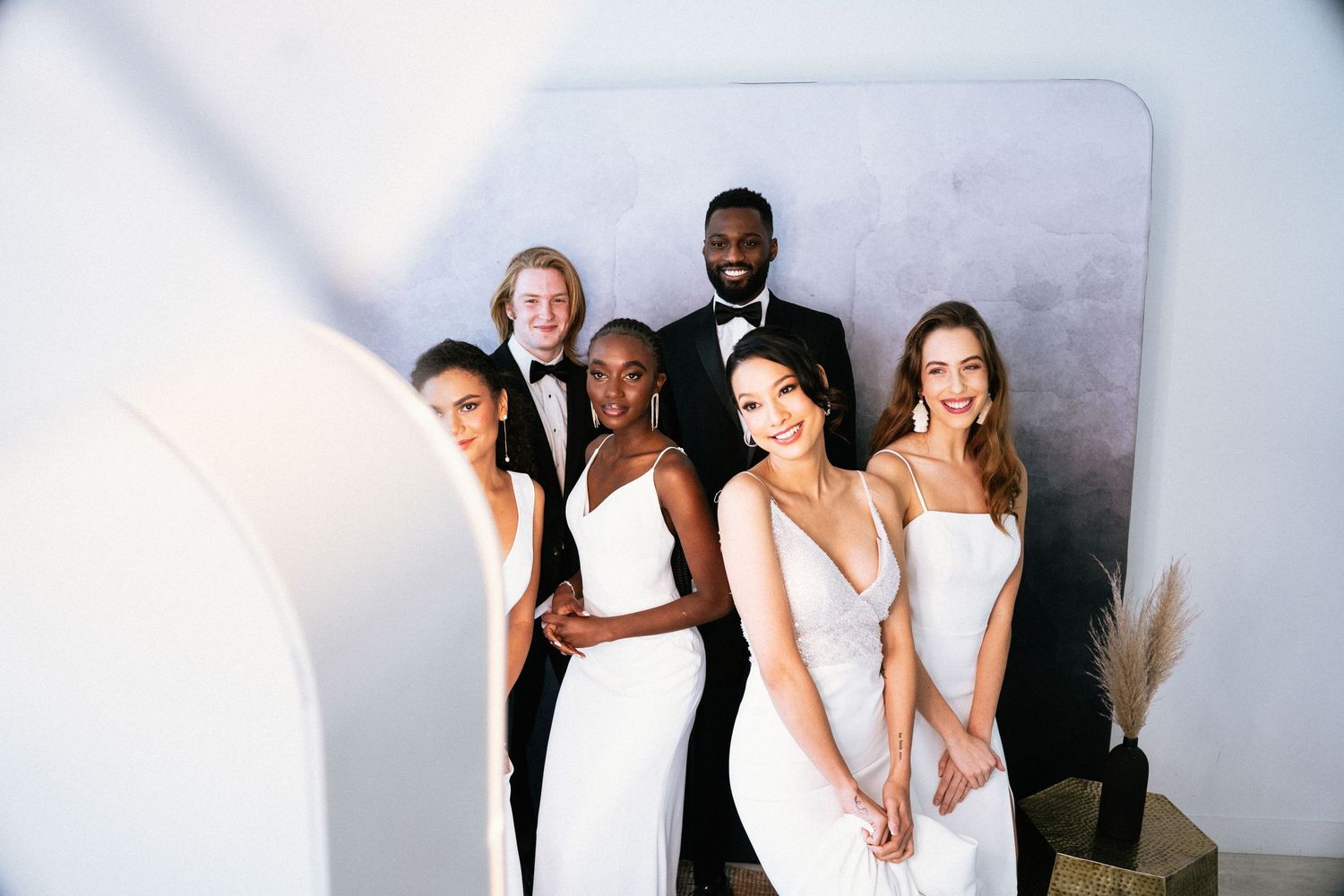 Wedding party members pose together in formal black and white attire for elegant group photos.