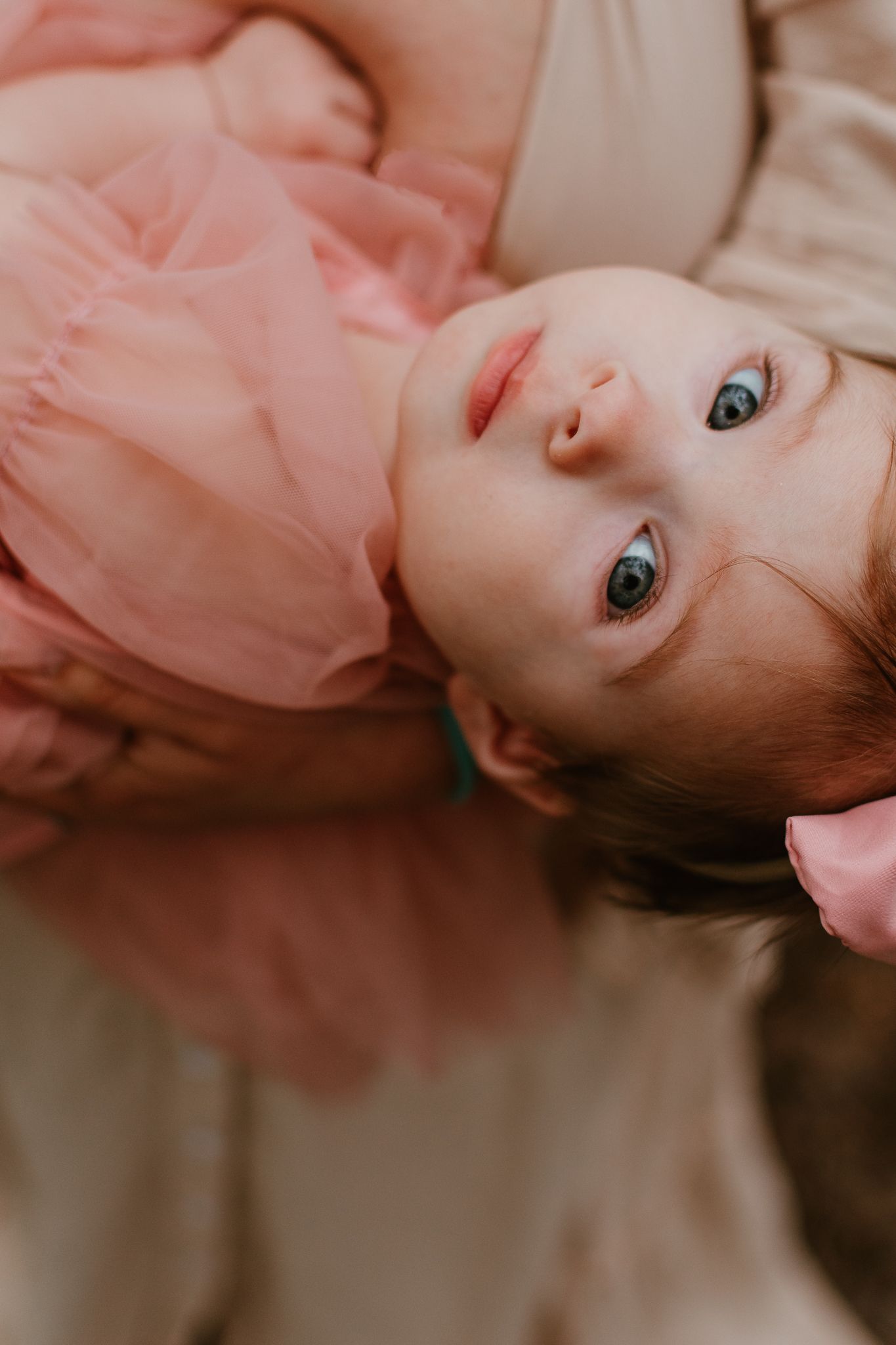 Close-up portrait in soft pink tones showing bright blue eyes.