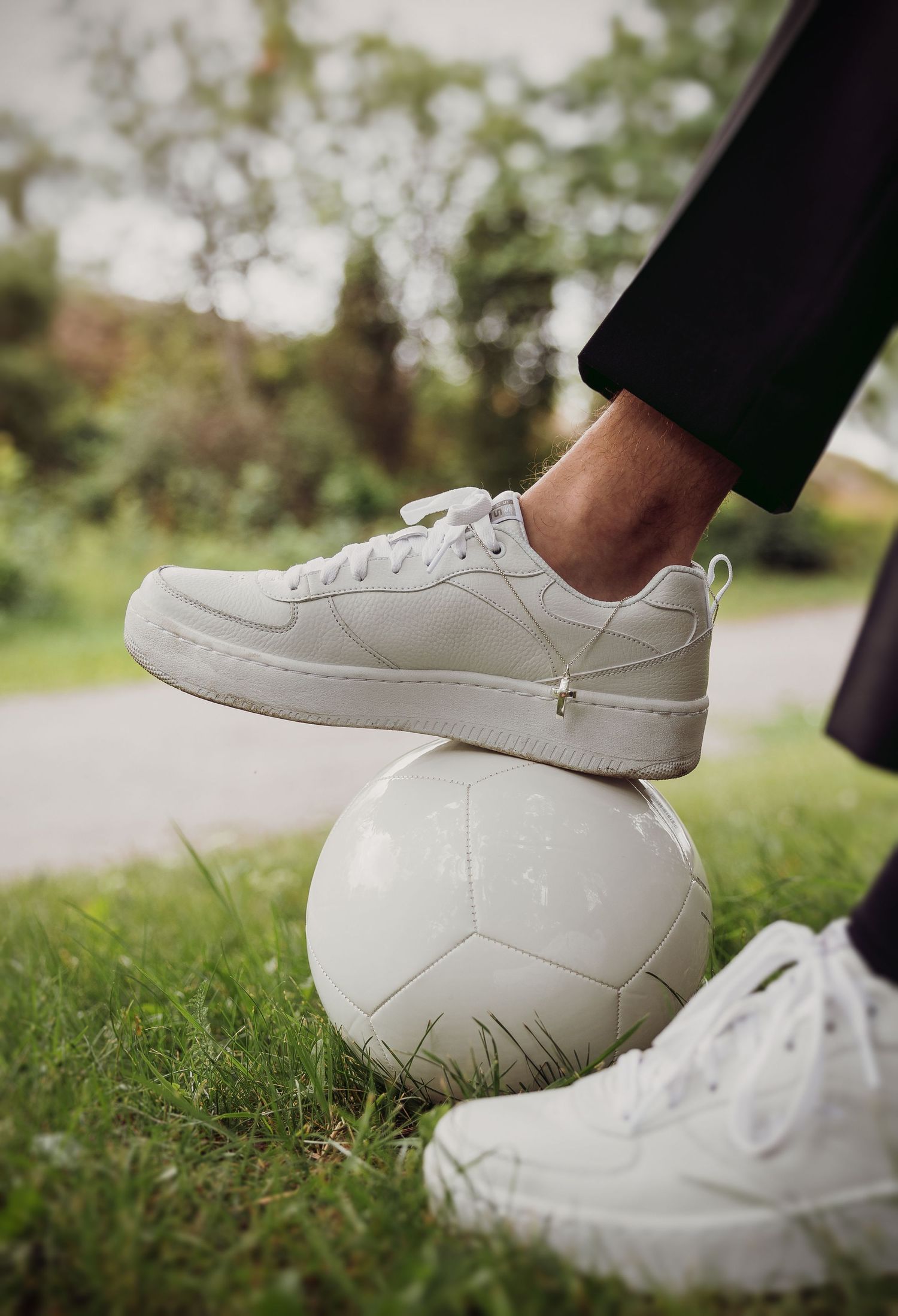 Close-up of white sneakers on grass during wedding photoshoot.