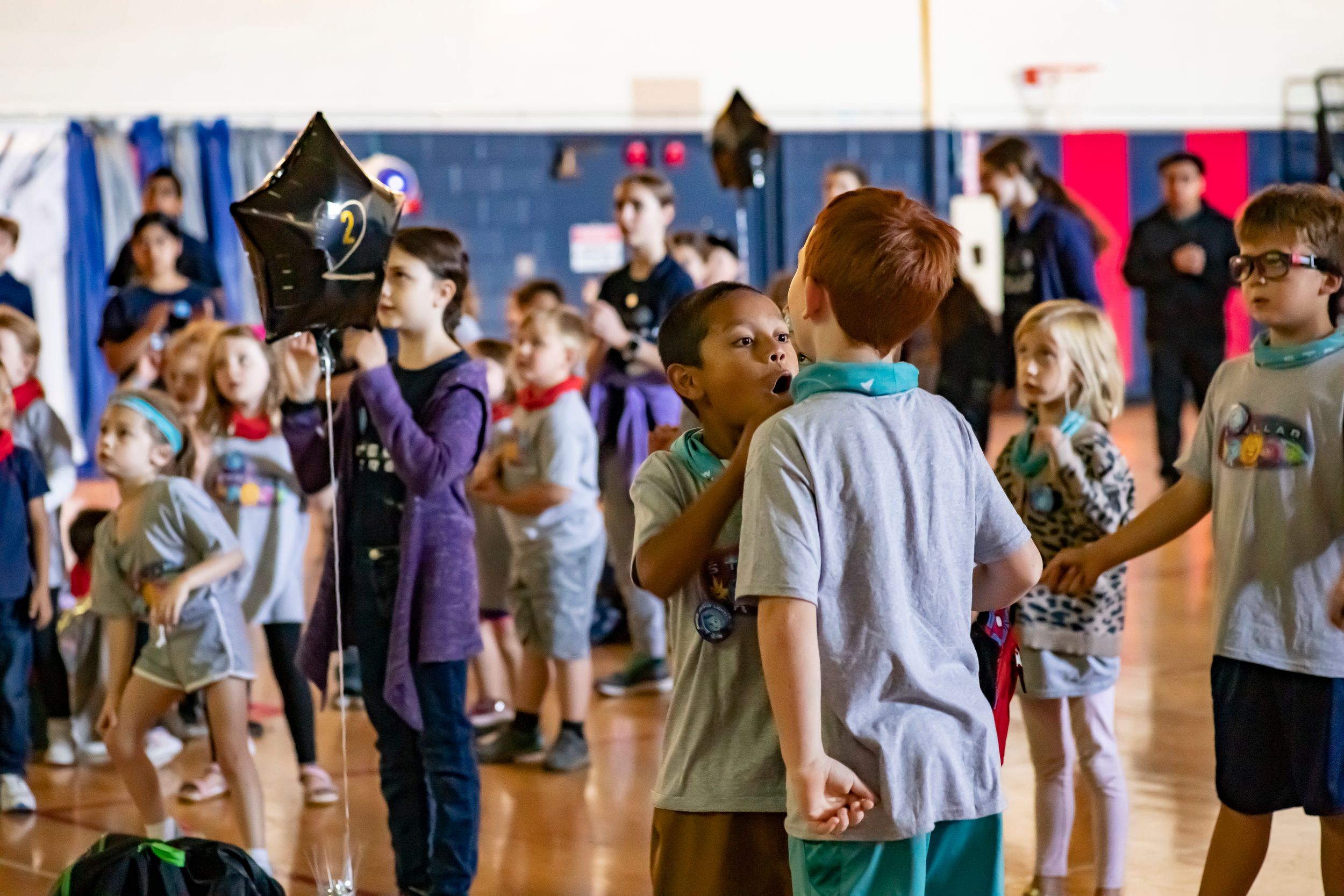 Students participating in a theatrical performance or costume event in a school gymnasium.