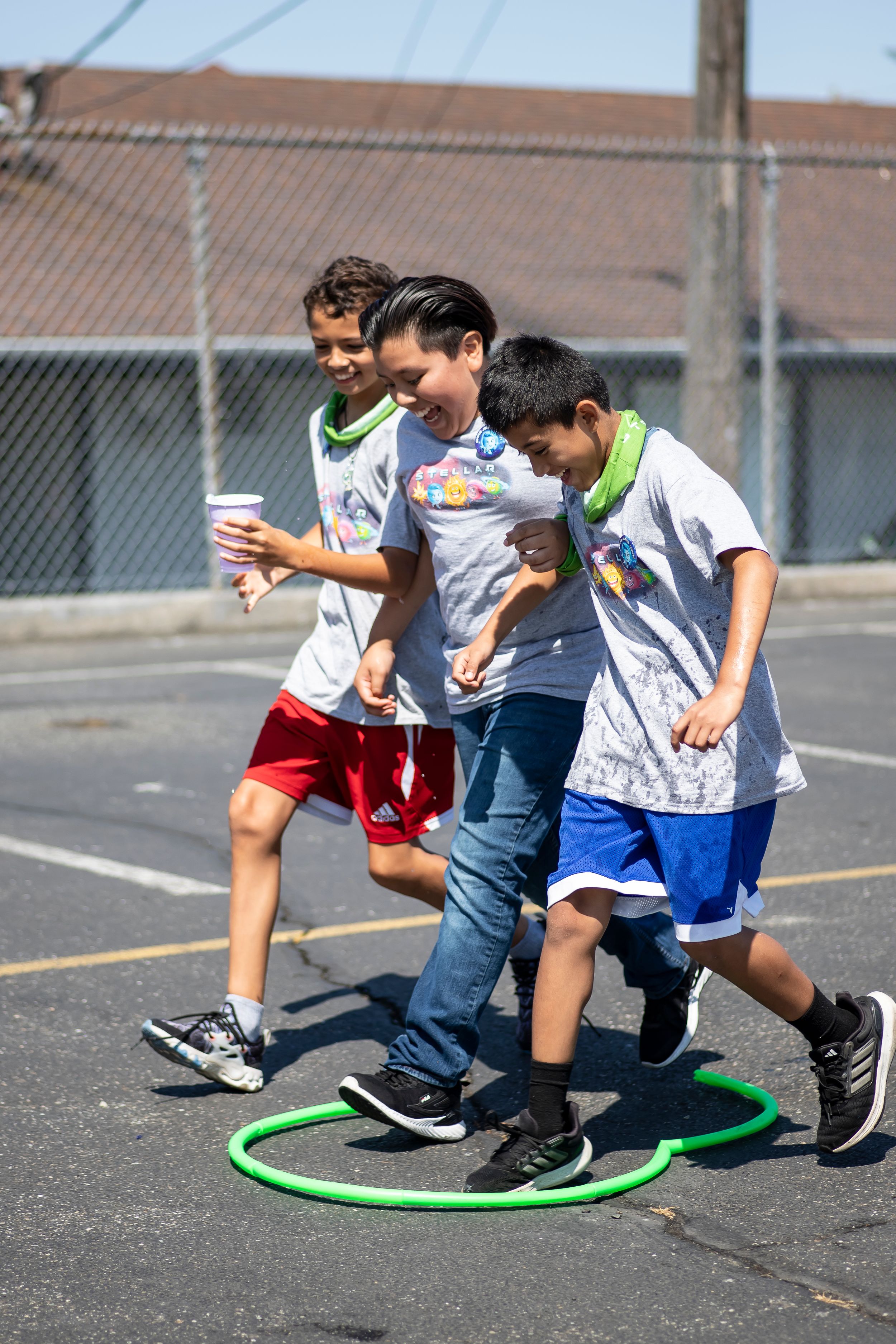 Students playing a movement game with green hoops in a school playground.