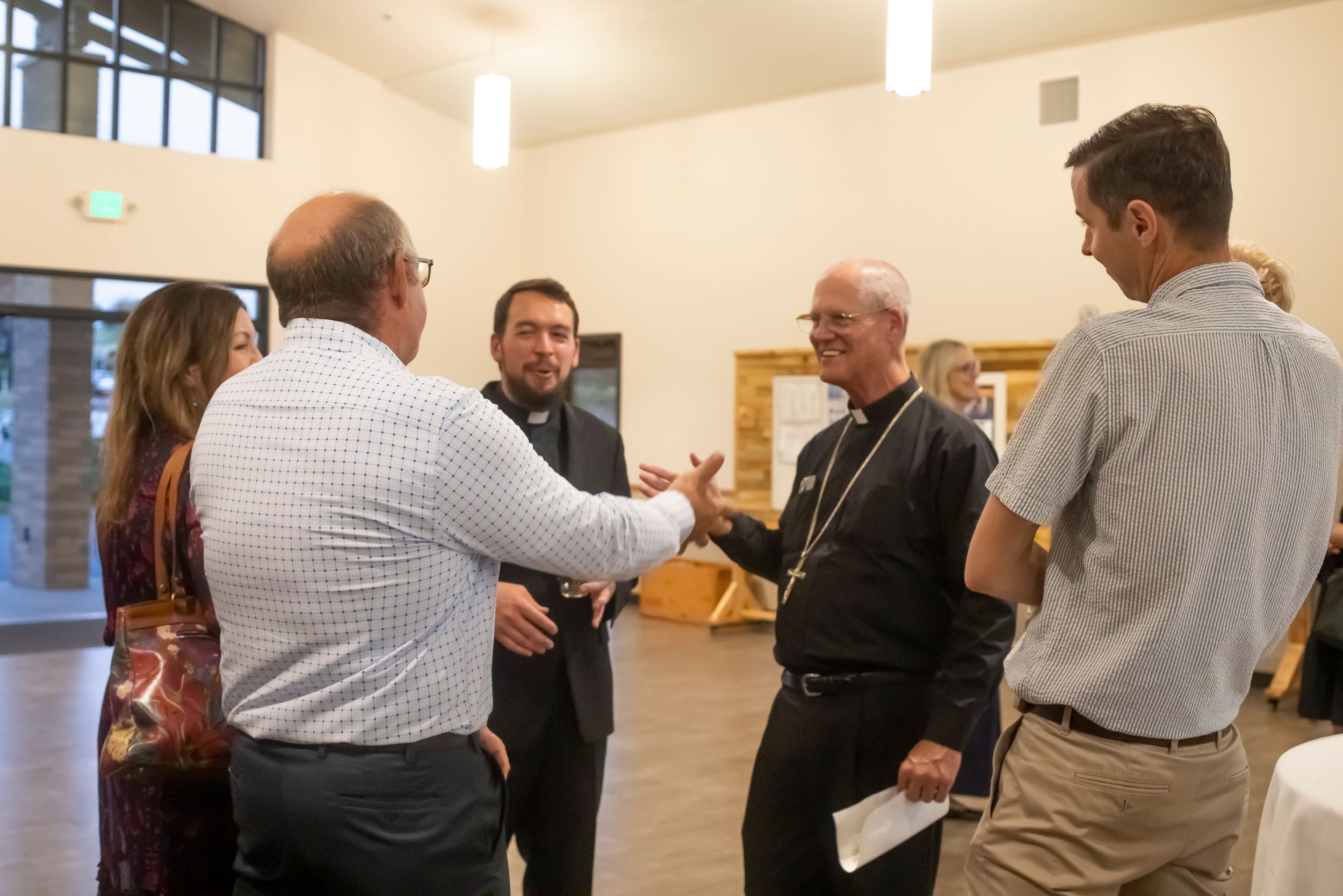A casual gathering of people conversing in a church fellowship hall.