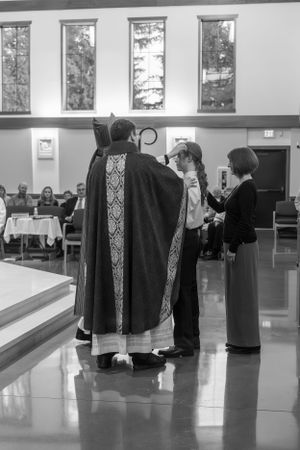 Black and white photo of clergy members in robes having a discussion in a church hall.