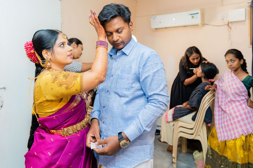 A woman in a pink and yellow sari performs a traditional ceremony with someone in a blue shirt.