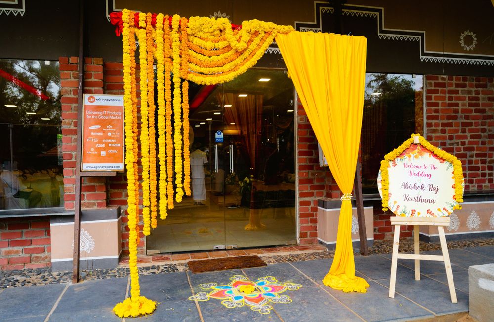 Yellow and orange marigold garlands decorate an entrance with black curtains.