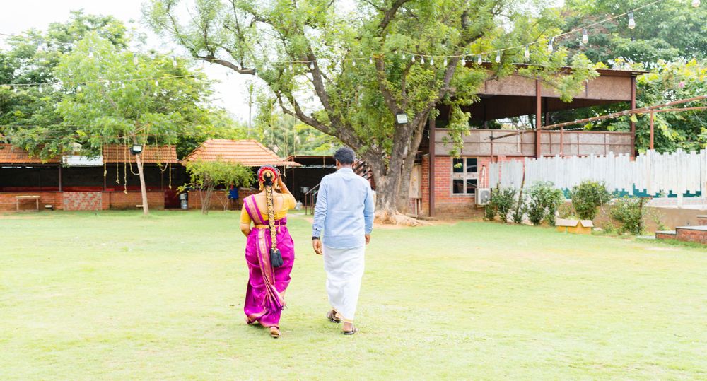 A couple walks through a green garden setting during a traditional ceremony.