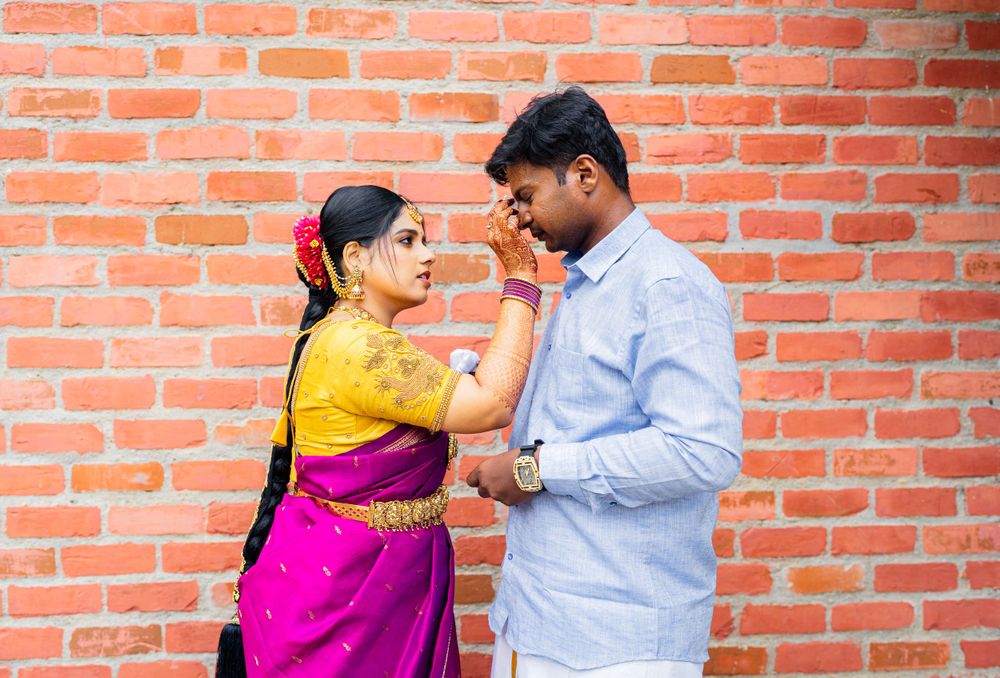 A romantic moment between a traditionally dressed Indian couple against a rustic brick wall backdrop.