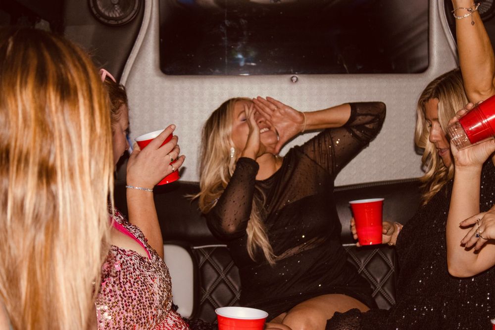 Women socializing with red solo cups inside a party bus at night.