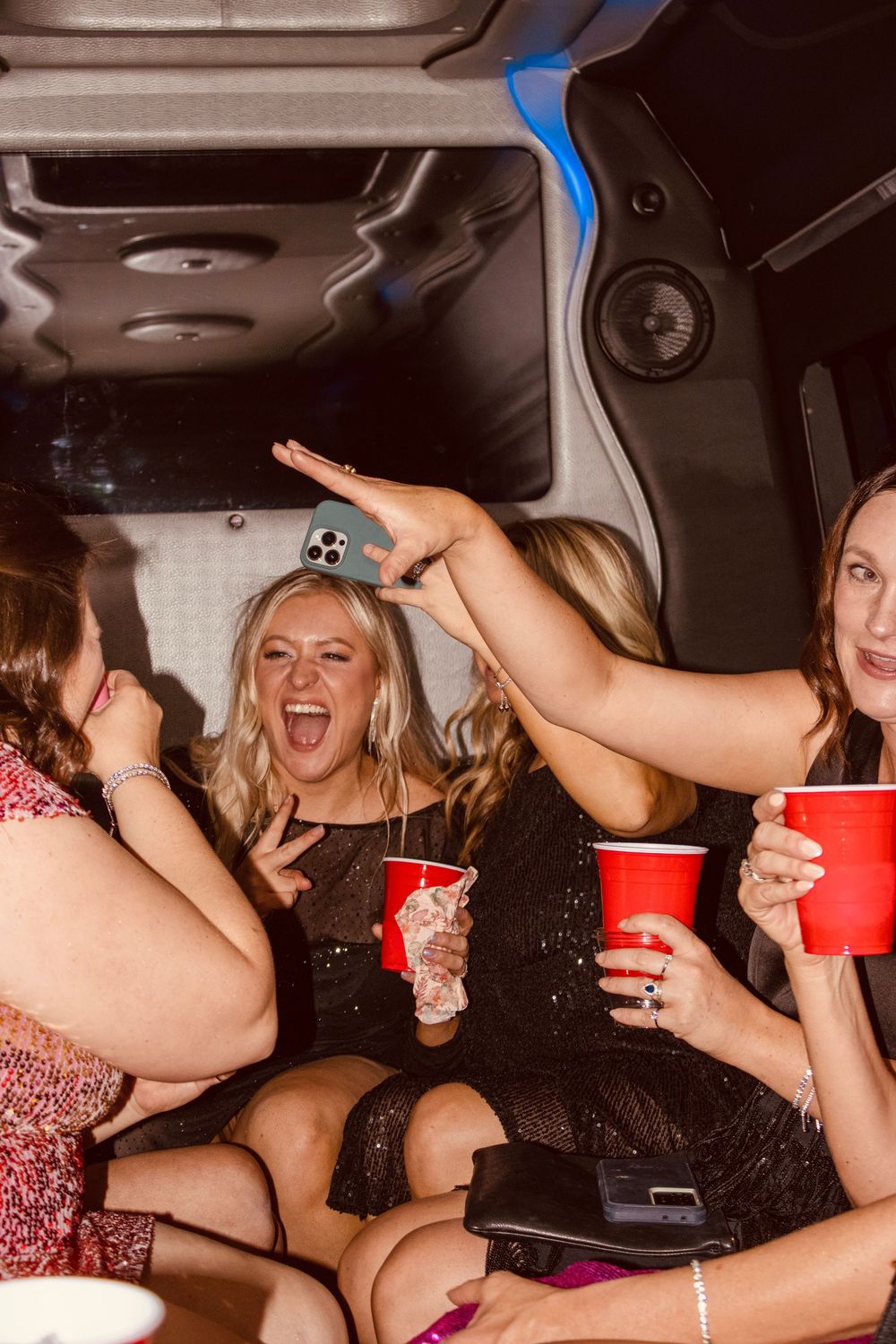 Women laughing and holding red Solo cups inside a party bus during a Las Vegas bachelorette celebration.