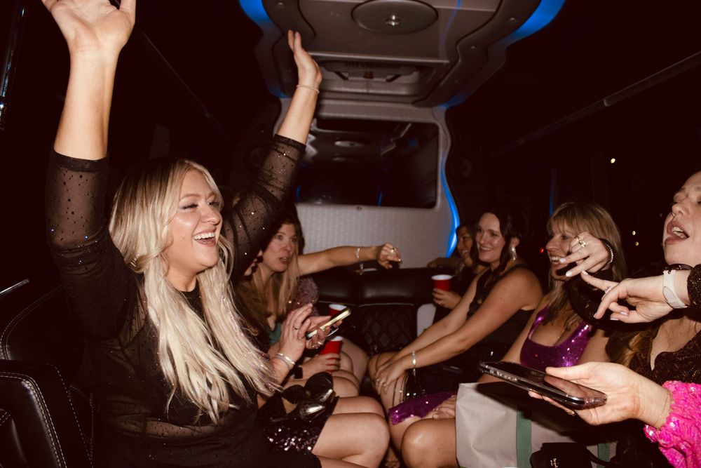 Women celebrating and dancing inside a party bus with colorful lights during a Las Vegas night out.