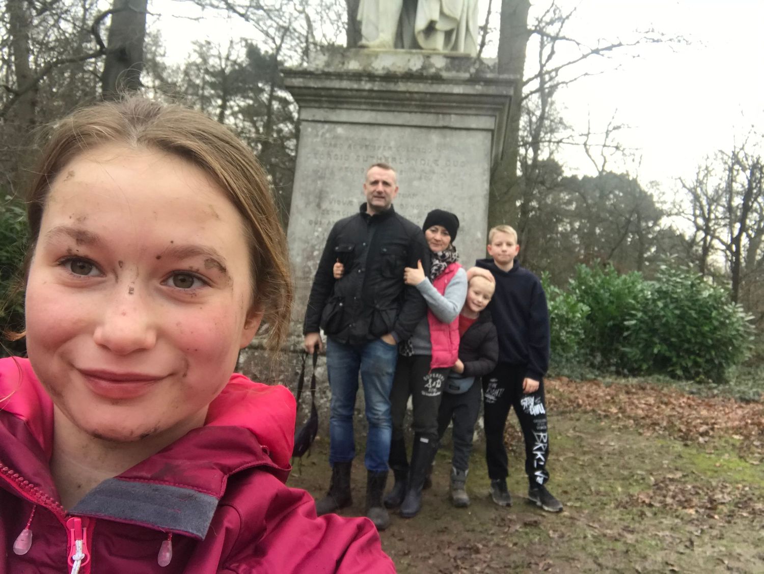 Group selfie taken near a stone monument in a park setting.