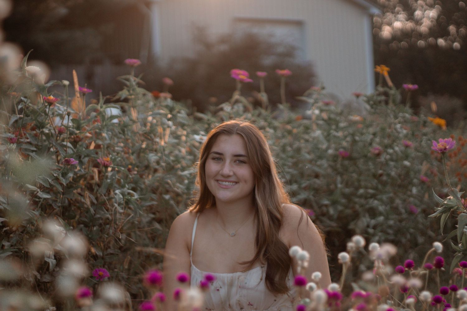 Woman smiling among colorful garden flowers during summer portrait session.