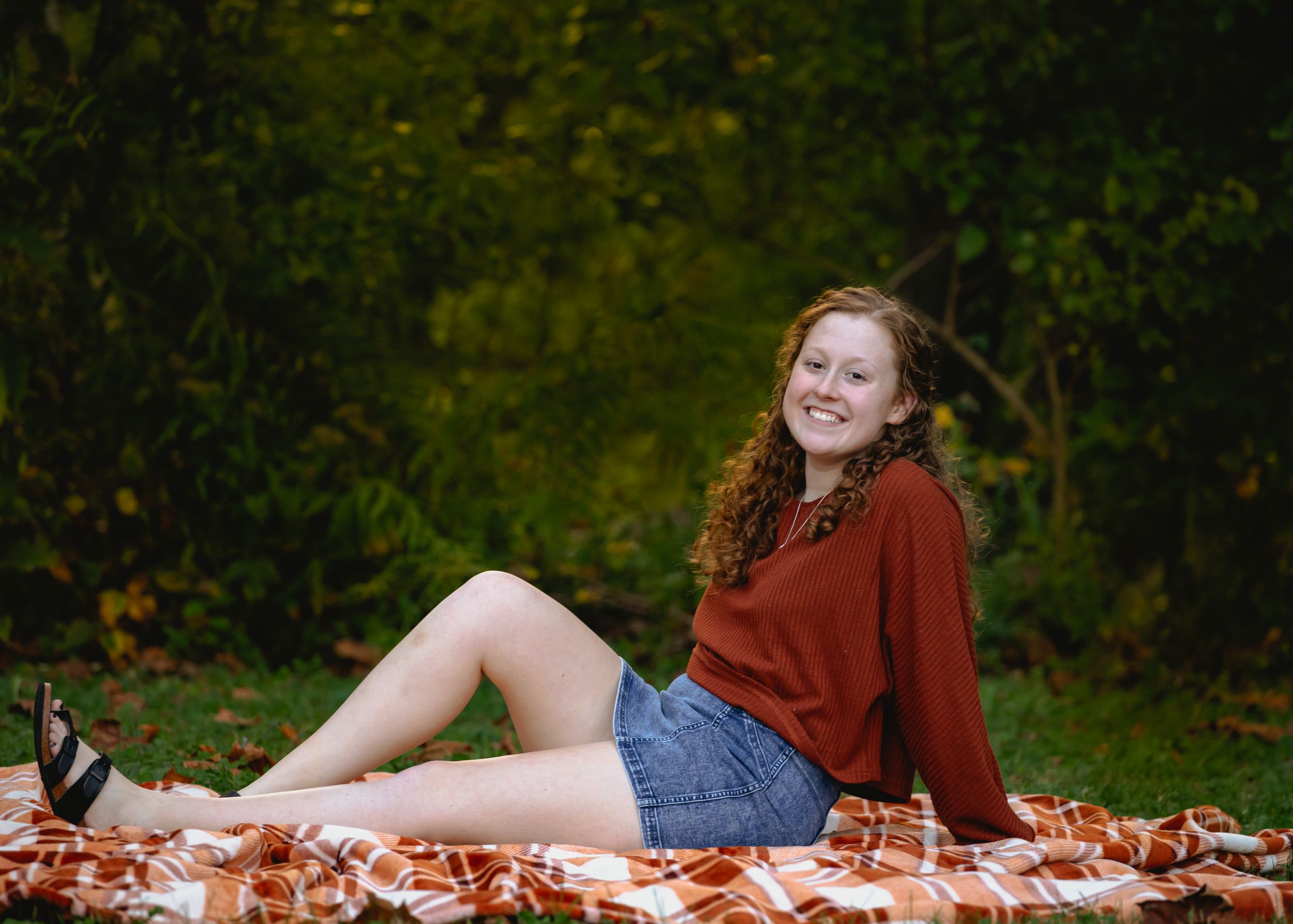 Outdoor photo session on an orange blanket with autumn scenery.