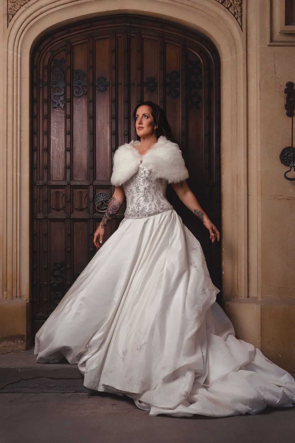 Bride in elegant white ball gown twirls in ornate architectural setting.