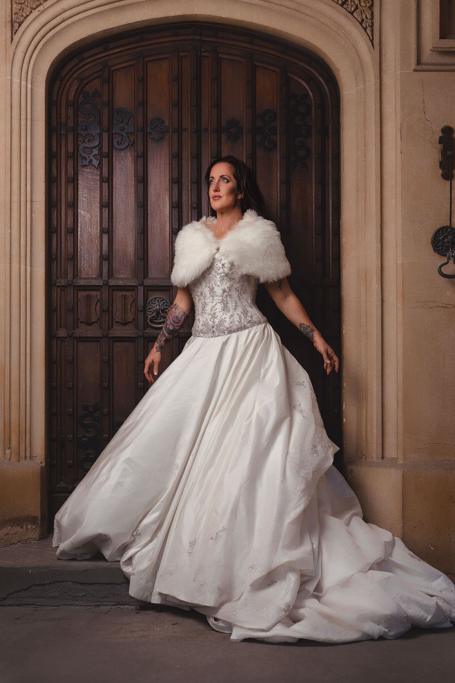 Bride in elegant white ball gown twirls in ornate architectural setting.
