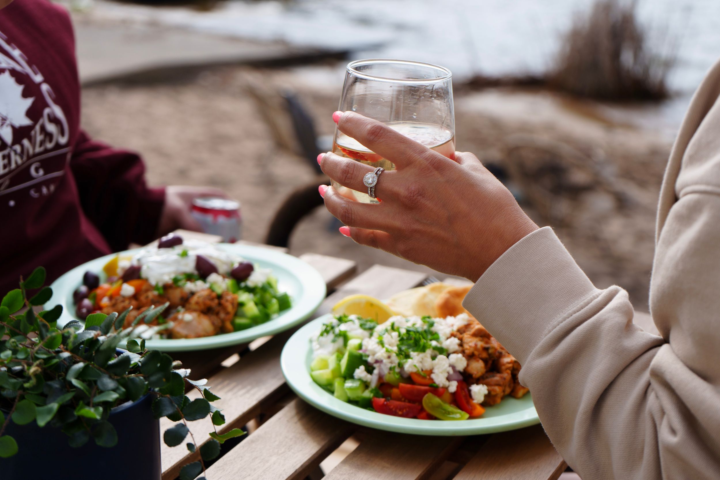 Casual outdoor dining scene with fresh salads and wine glass on rustic table.