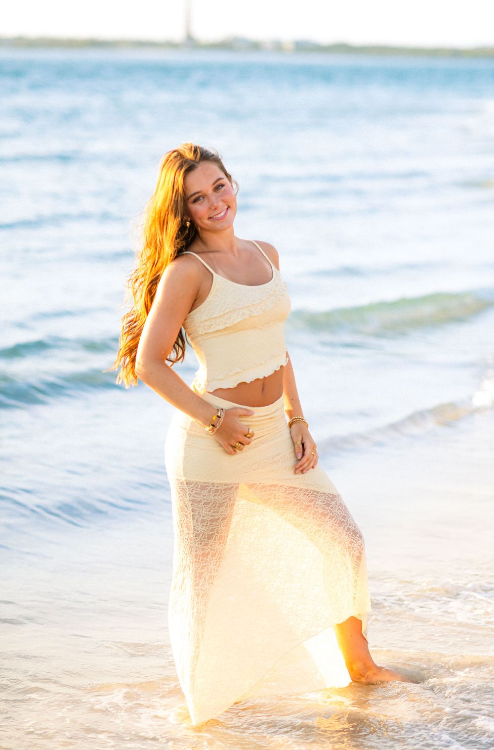 Woman in white dress twirling on beach during golden hour.