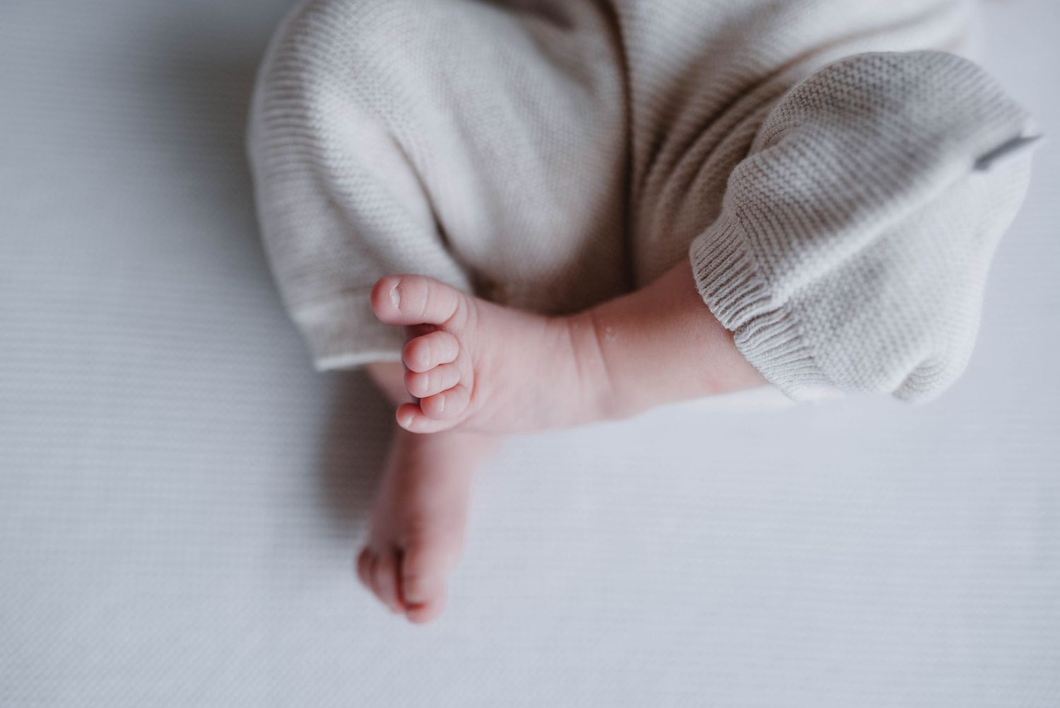 Minimalist close-up of baby's tiny foot against white background.
