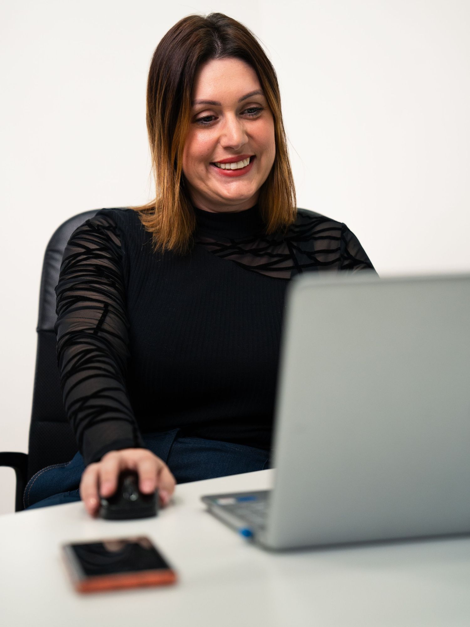 Person in black top working on laptop with casual, relaxed expression.