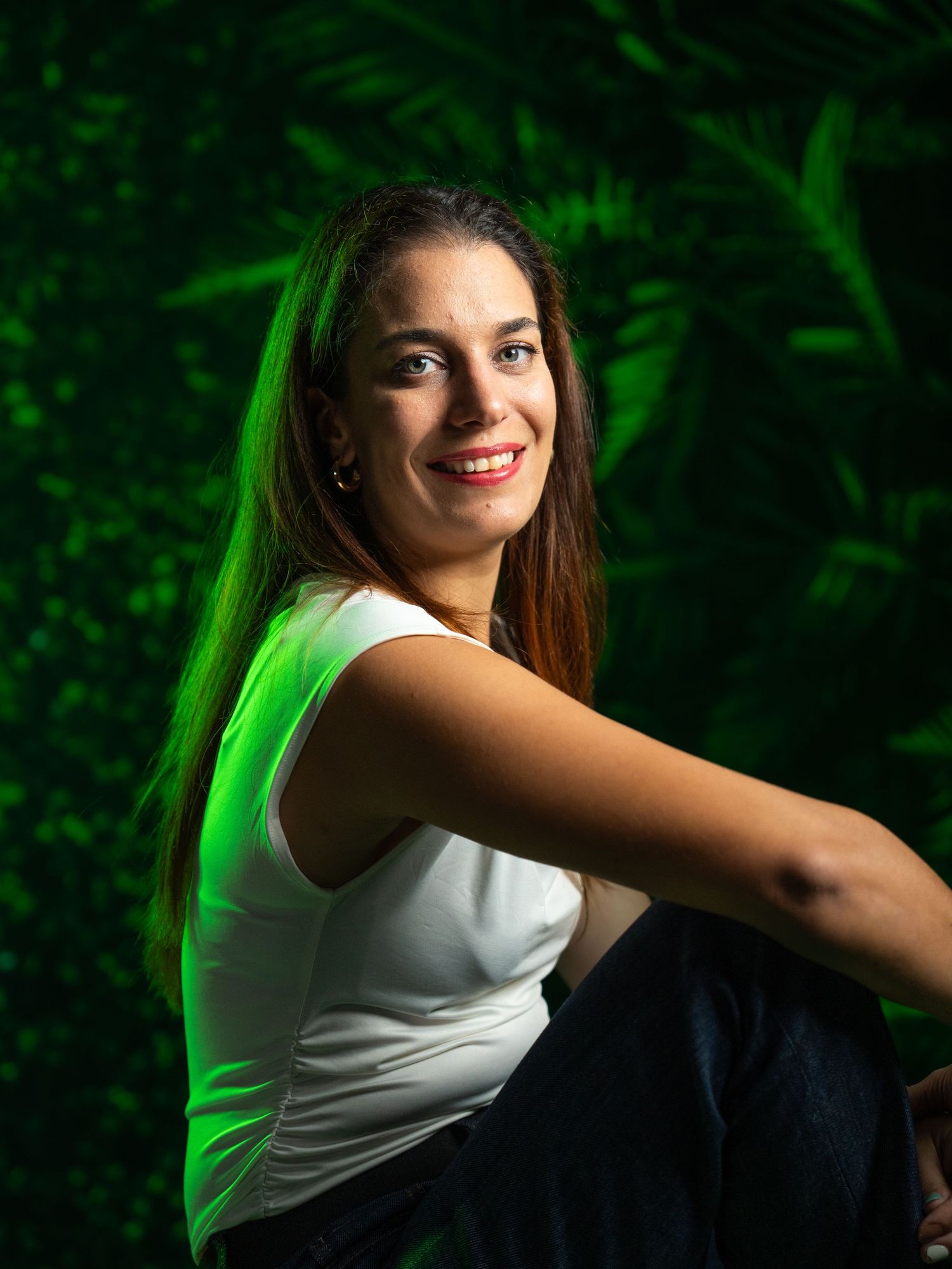 Creative portrait with green neon lighting effects and white outfit against dark background.