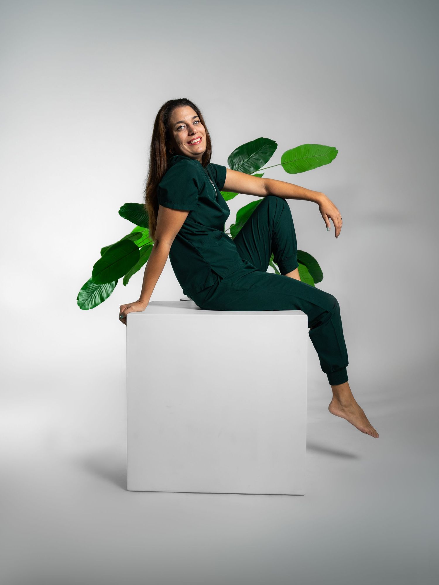 Studio portrait on white background with person lounging on geometric blocks with tropical leaves.