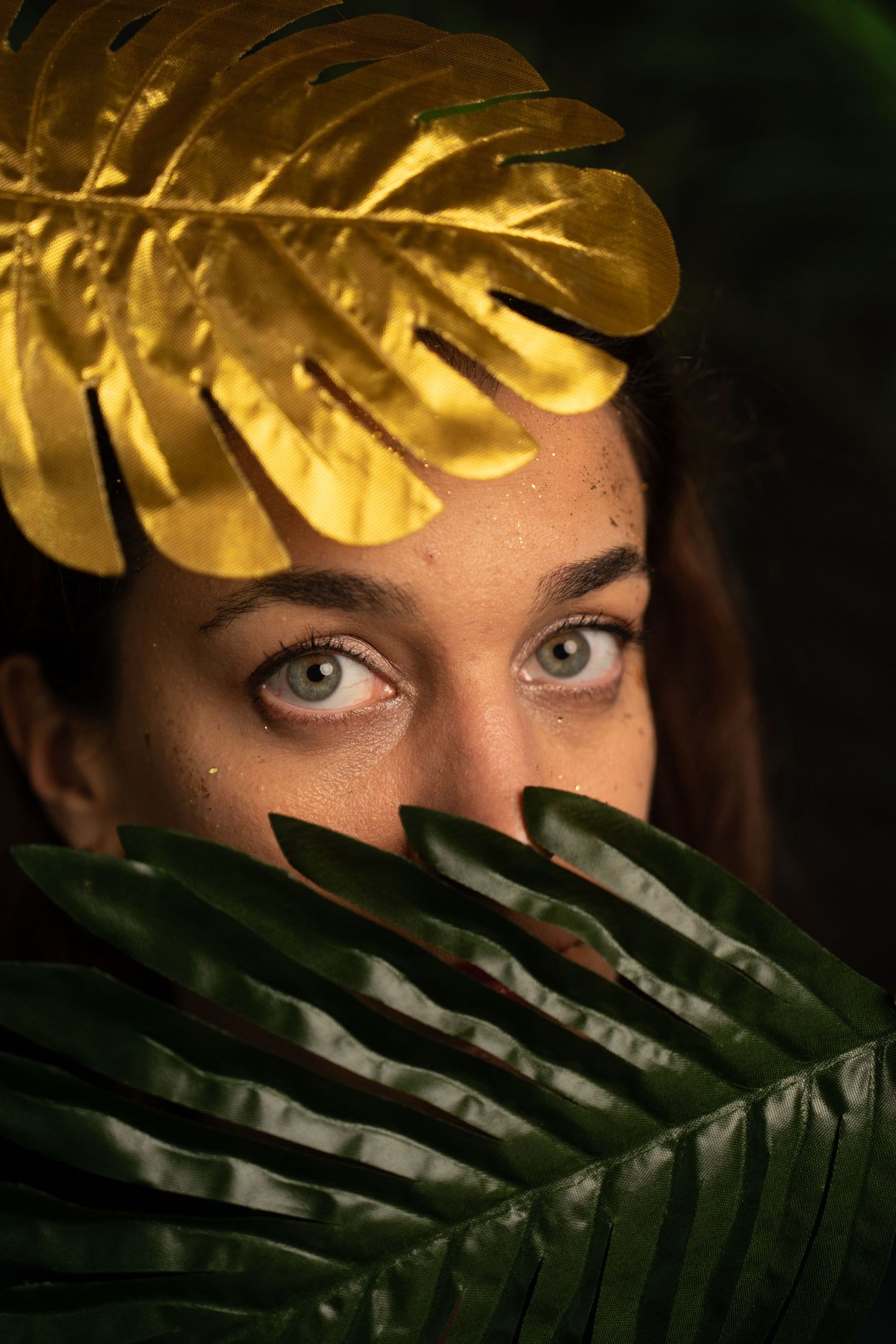 Creative close-up with gold monstera leaf and palm fronds creating natural frame.