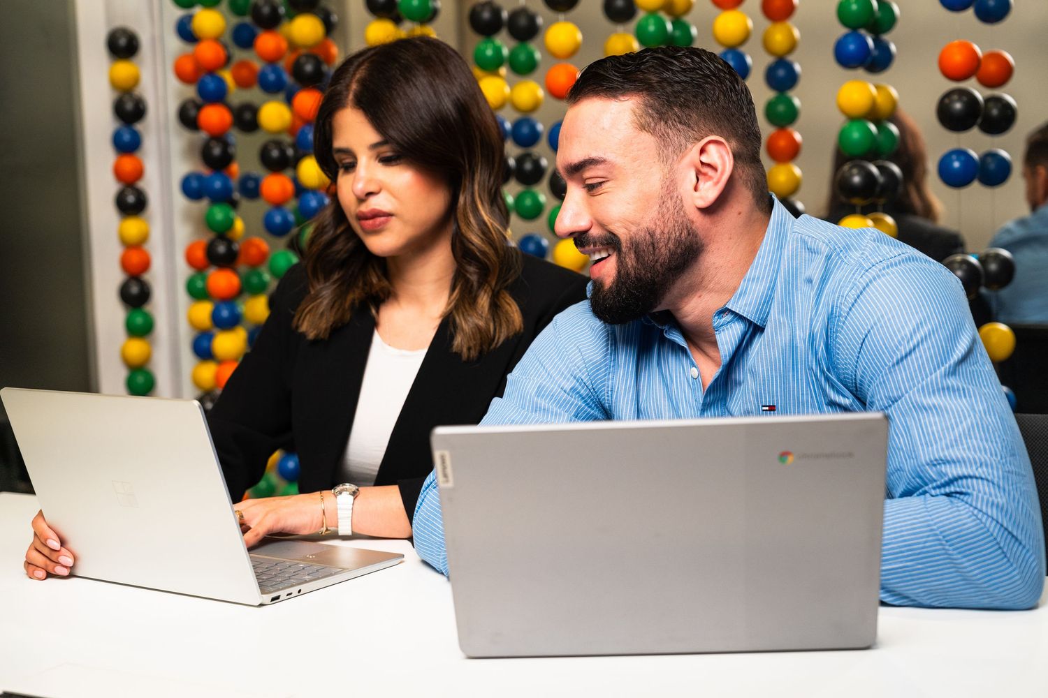 Office meeting scene with colorful balloon wall backdrop and laptop computers.