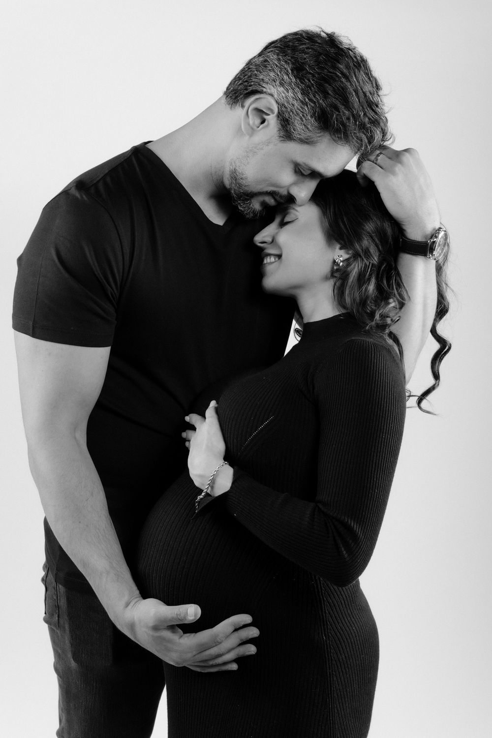 A series of intimate black and white maternity photos showing a couple embracing in silhouette against a light background.