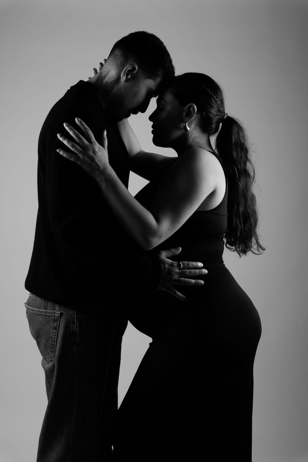 Artistic black and white photo series showing silhouettes of a romantic couple in intimate embrace against plain background.