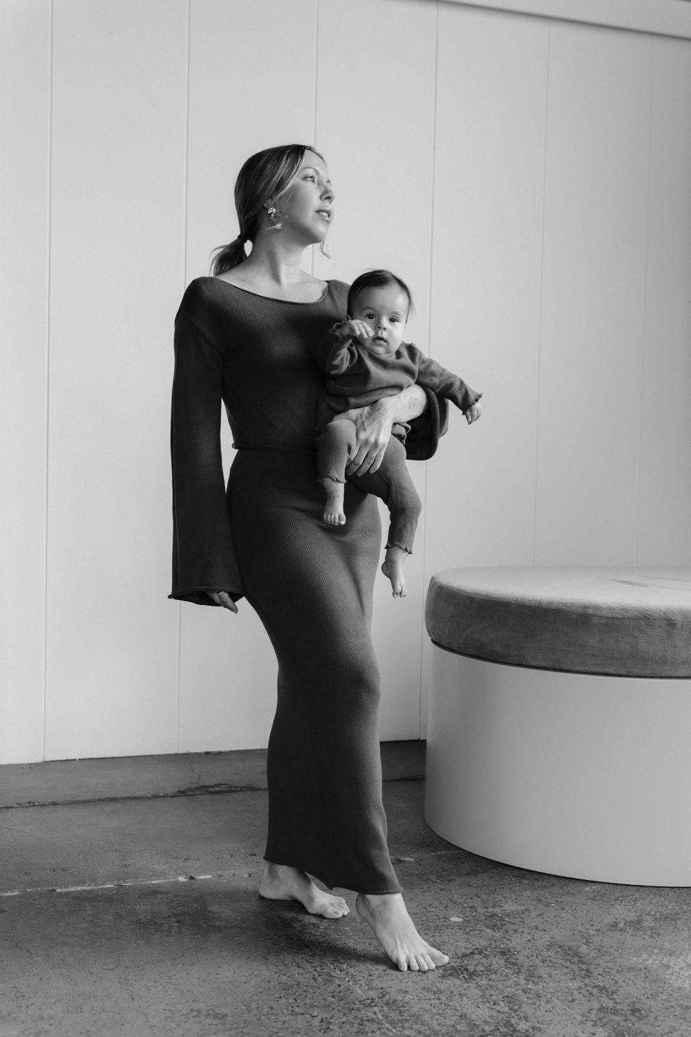 A series of black and white photos showing a person in a dark dress holding and interacting with a small baby.
