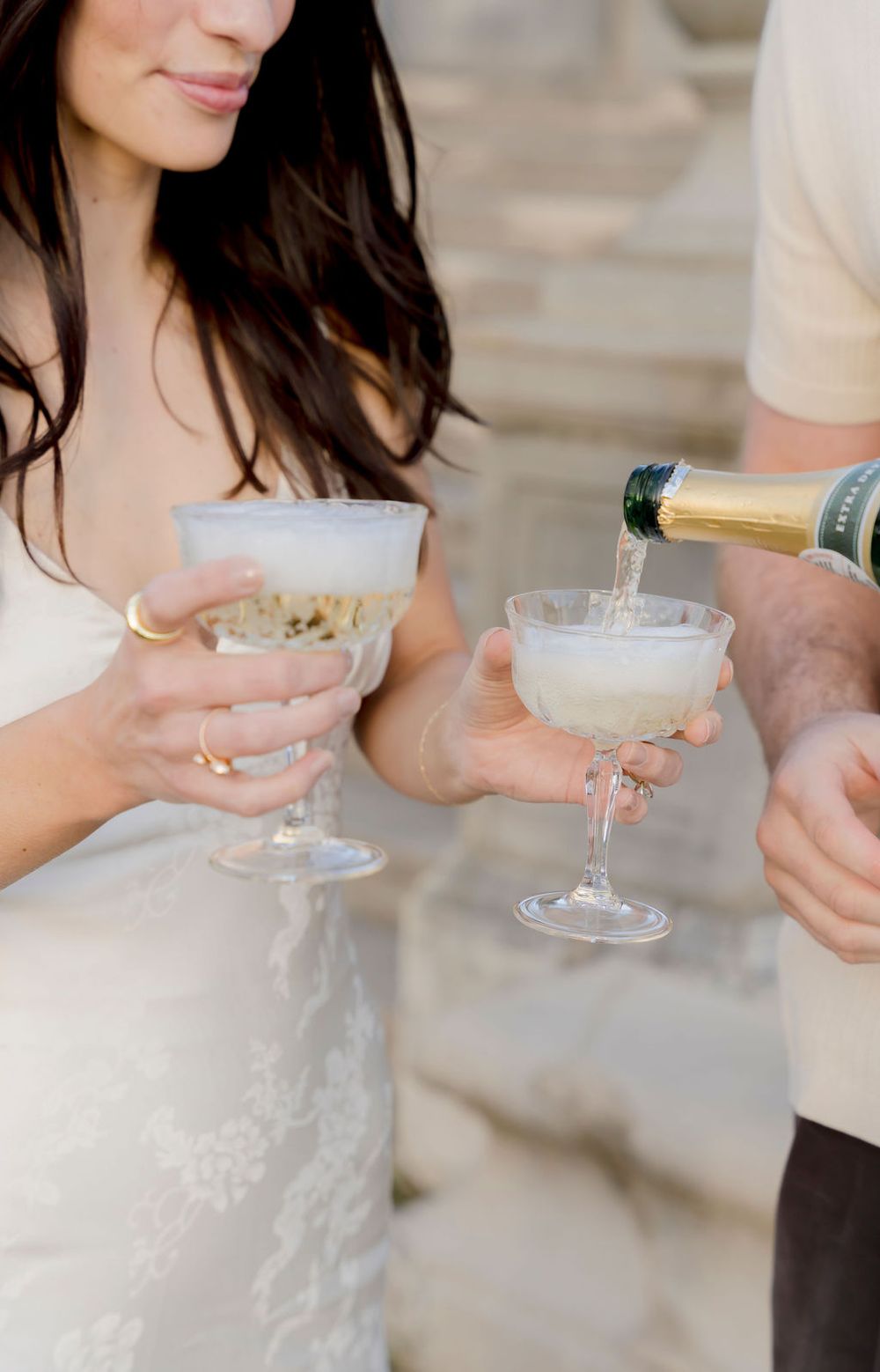 Hands holding elegant champagne coupes with frothy cocktails during an elegant celebration.