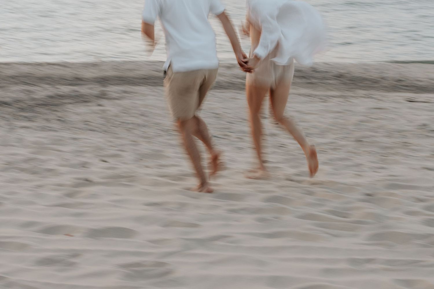 Blurred motion shots of people walking on a sandy beach at sunset.
