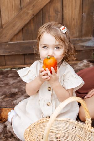 little girl, holding tomato, outdoor photography, fall.