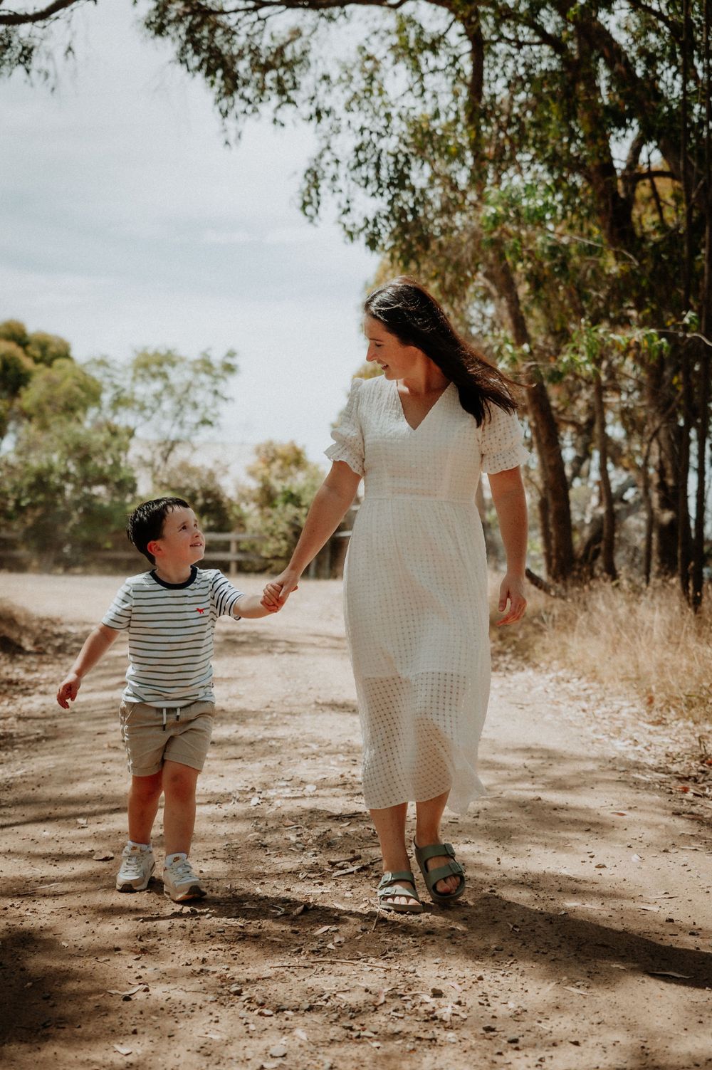 Family walking together on shaded dirt path through eucalyptus trees.
Altona Family Photographer Melbourne
