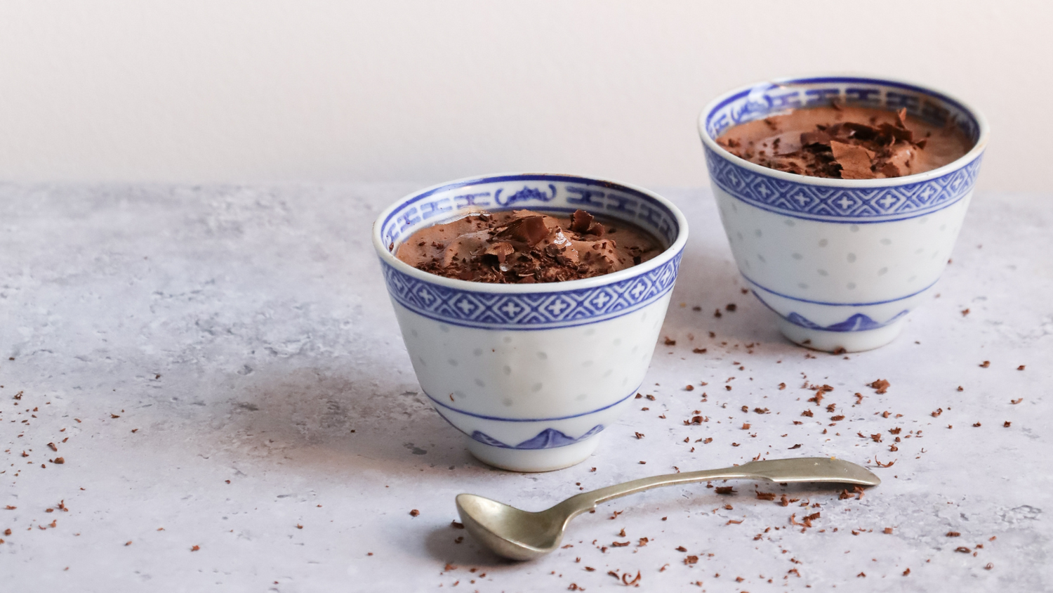 Blue and white porcelain bowls containing dark liquid on light surface.