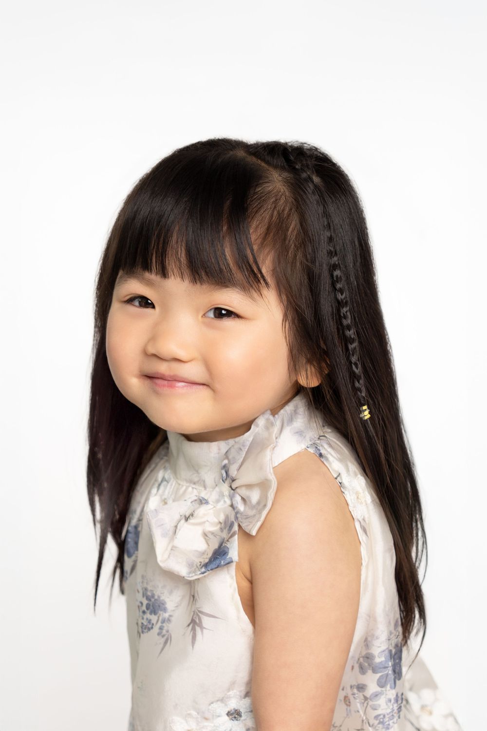 Child in white floral dress making playful expressions.