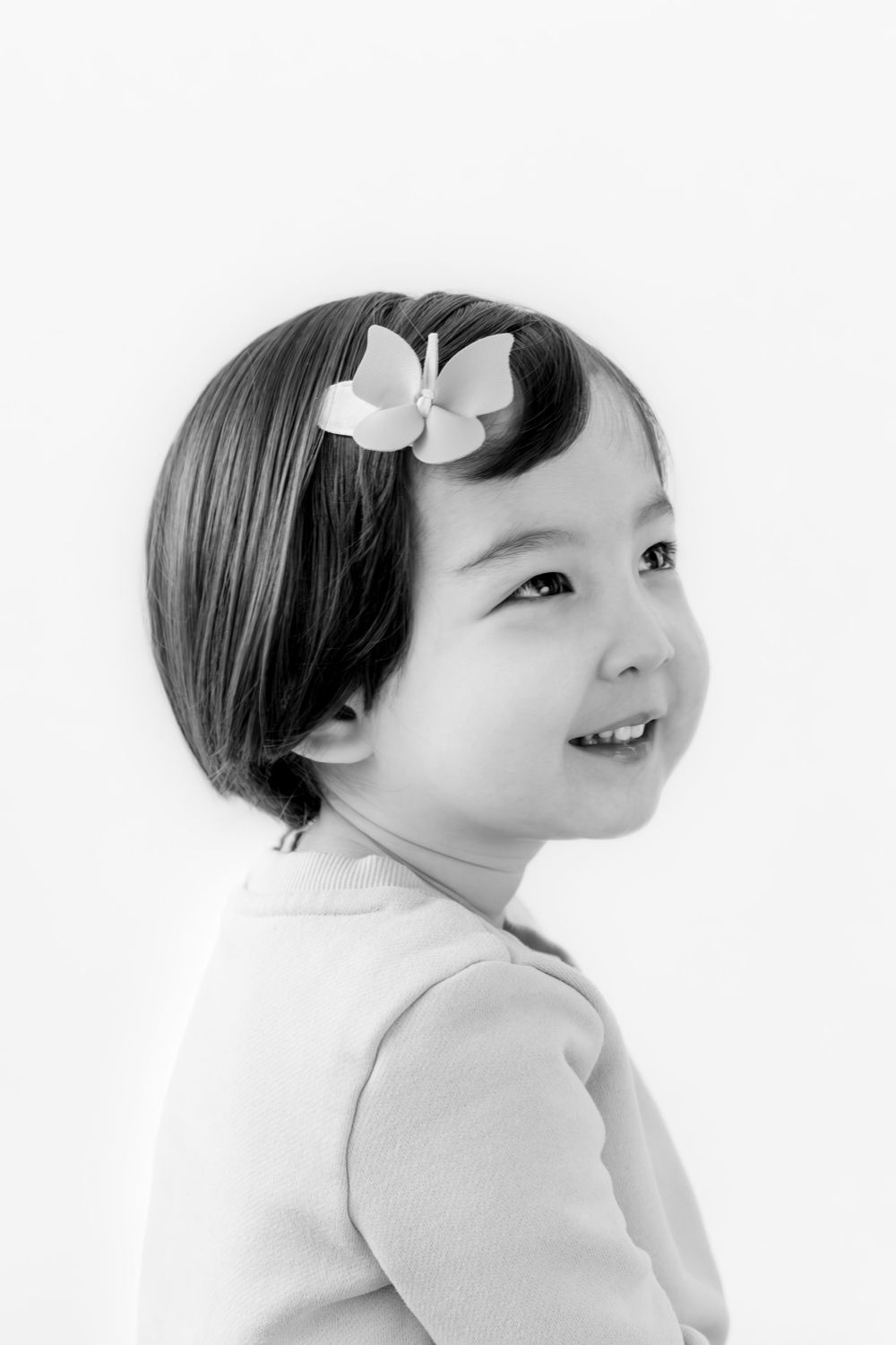 A series of black and white portraits showing a smiling figure with short dark hair and a white bow accessory.