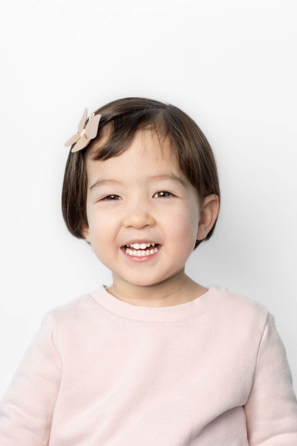 A child in a light pink sweater shows different expressions in a series of four photos against a white background.