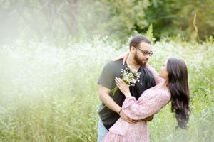 A romantic engagement photo in a dreamy meadow with soft lighting and wildflowers.