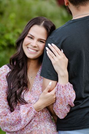 A close-up engagement portrait showing a woman smiling while holding her partner.