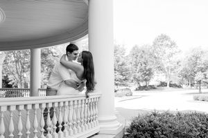 Black and white photo series of a romantic wedding couple posing on a grand balcony with elegant columns and railings.