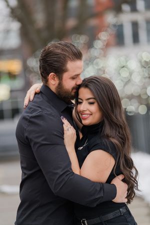 A couple shares intimate moments while embracing and dancing together outdoors with bokeh lights in the background.