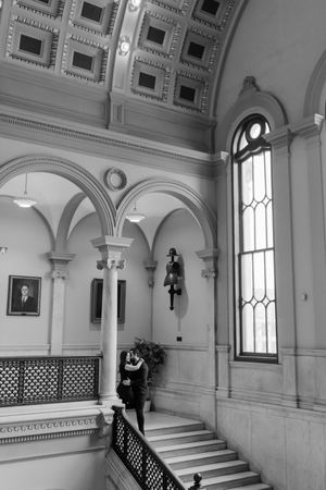 Elegant white marble staircase with ornate arches and windows in a classic architectural interior hallway.